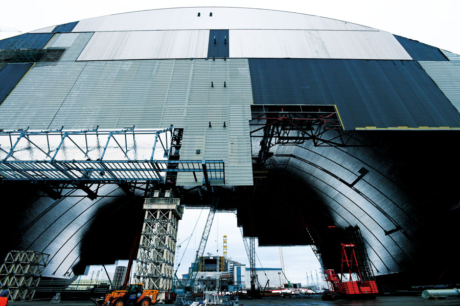 2016年中に建設工事を終え、チェルノブイリ原発3、4号炉（写真背後）を覆う予定となっているドーム（写真手前）。巨大事業のため計画は二転三転したが、フランスを中心とするヨーロッパの共同事業体NOVARKAによって進められている。写真はすべて、チェルノブイリ地区、ウクライナ。 2016年1月14日