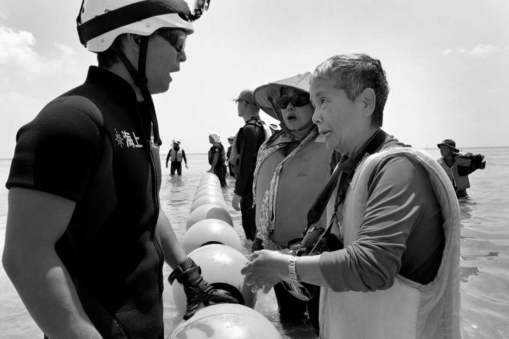 大潮の日、辺野古の海はリーフまで歩いて行けた。若い海保職員を説得する宮里洋子さん。2014年9月9日