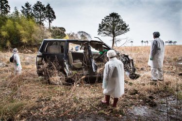 津波に流された汐凪さんの母、深雪さんの車を見る家族。車は自宅から300メートルほどのところに今もある。何か手がかりはないかと家族は車の中を何度も見返している。2014年3月29日