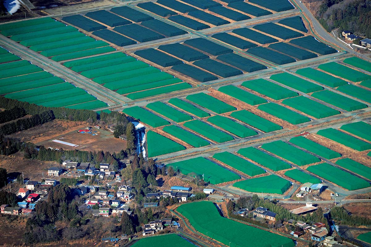 汚染物を入れたフレコンバッグが並ぶ仮置き場が、富岡町に広がる。富岡町は事故で7040世帯の住民が避難したが、街に戻る希望を出しているのは回答数3257世帯のうち16パーセントに過ぎない（2016年10月25日「富岡町住民意向調査調査結果（速報版）」による）。福島県富岡町上空。2017年1月25日